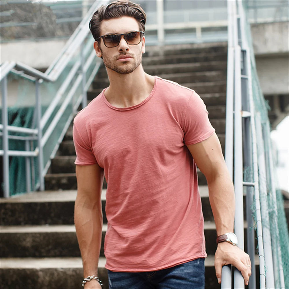 Man wearing pink 100% cotton casual T-shirt with sunglasses on outdoor stairs.